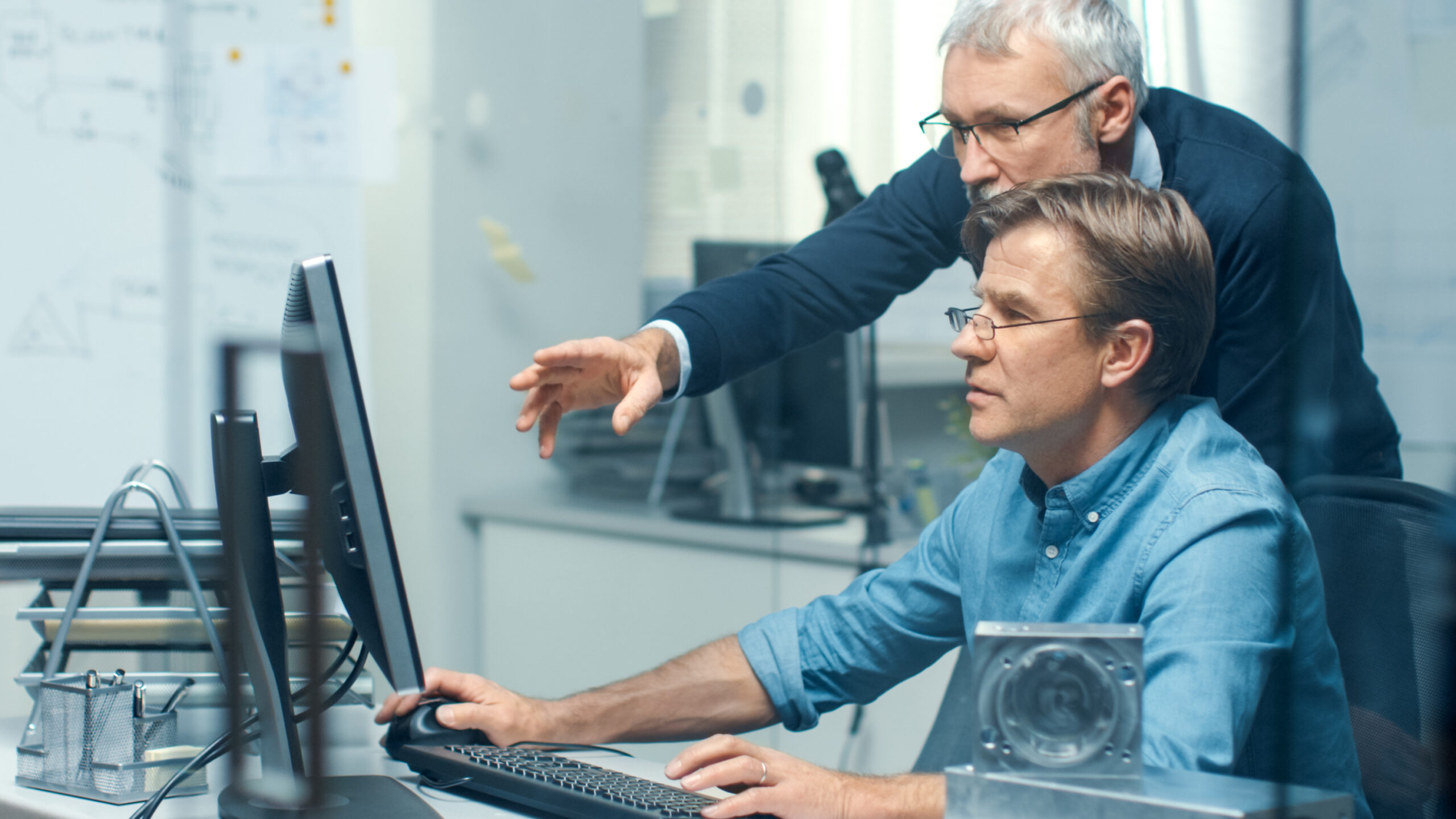Two machinists learning GibbsCAM at a workstation